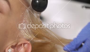 A yakın çekim geri yıkama havzasında sarışının boyalı saç yıkama bir mavi kauçuk eldiven içinde el. Saçlar yıkanır ve duş durulanır