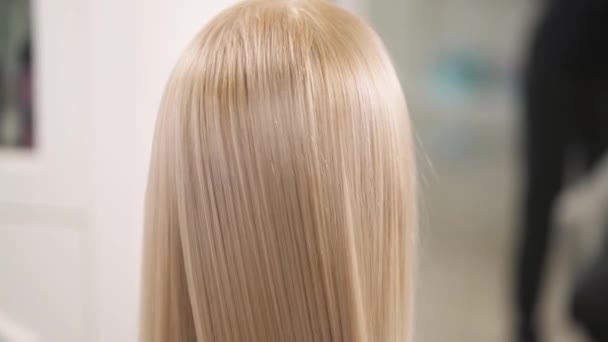 Близкий задний вид волос блондинки, расчесанный щеткой для волос до длины. Камера медленно движется сверху вниз . — стоковое видео