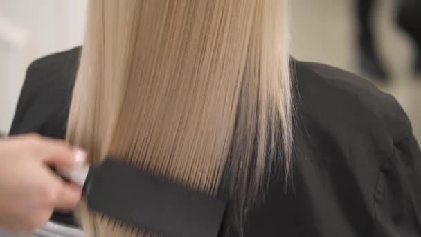Близкий вид на концы волос блондинки, причесанный расчёской. Камера движется снизу вверх и замерзает в верхней части головы . — стоковое видео