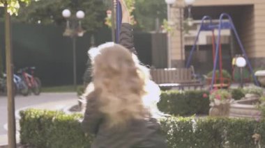 Dışarıda güzel bir sarışın kız oynar. O bir kutbuna tutar ve çevresinde twirls, durur ve yine başardı. O zaman o kamera gülümseyen içine görünüyor.