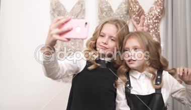 Uzun kıvırcık sarı saçlar iki güzel kızla bir selfie alıyor. Büyük olan onları önünde bir telefon tutar. Onlar V işaretleri yapmak, komik suratlar çekin, dilleri göster ve tavşan kulakları yapmak.