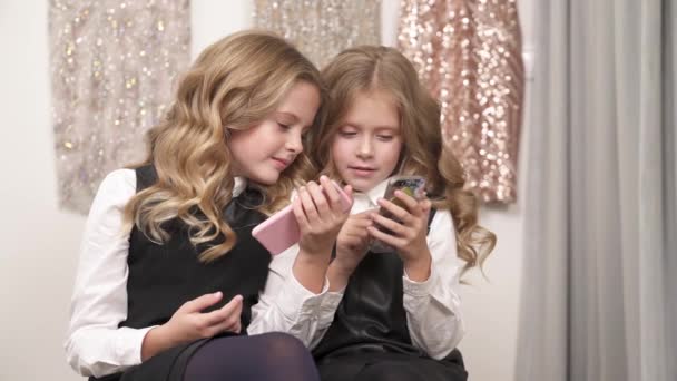 Twee Mooie Blonde Meisjes Zitten Bank Binnenshuis Beide Telefoons Houden — Stockvideo