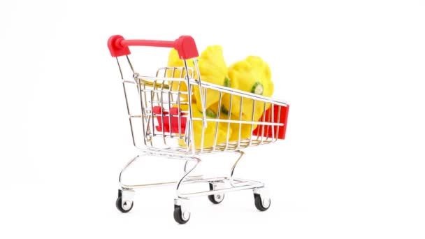 スーパー マーケットのトロリー 黄色の菓子鍋南瓜とショッピングカート 白い背景上に分離 クローズ アップ マクロ — ストック動画