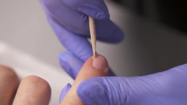 Manikürcü cuticles üzerinde adam ahşap kütikül itici stick kullanarak tırnak ilgileniyor Close-up.