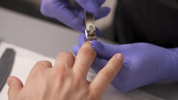 用紫色手套特写美甲师的手使用指甲钳修剪男人的指甲 — 图库视频影像