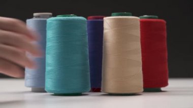 Çok renkli bobin koyu arka planı beyaz yüzey üzerinde duran bir portre. Bir el sol uzakta alır