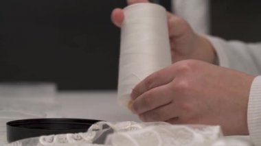 Erkek makas tutan ve bobin, beyaz iplikle dinlenmek eller iğne deliği geçen, bu kesim ve dikiş masanın üzerinde yatan dantel ile devam edin