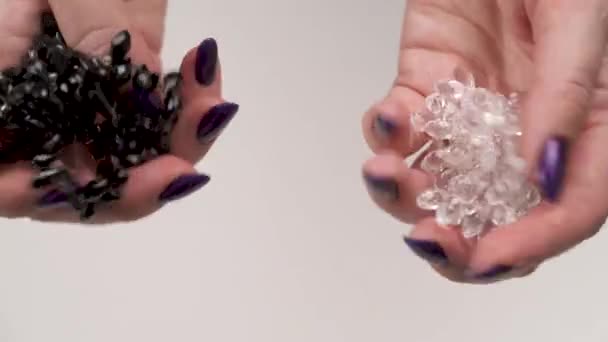 Dwie kobiety ręce trzymając czarny i crystal zroszony ciągi i toczenie, skręcanie, umieszczając je razem, aby mieć lepsze spojrzenie — Wideo stockowe