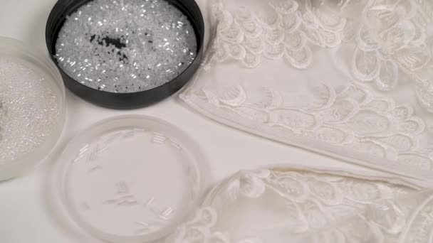 Ένα κοντινό πλάνο γυναικεία χέρια ράψιμο λευκό χάντρες ξαπλωμένη στο στρογγυλό καπάκι μπροστά της διακοσμημένη ύφασμα — Αρχείο Βίντεο