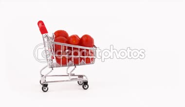 Süpermarket arabası hareket kırmızı üzüm domates kazık su damlaları ile dolu. Beyaz arka plan üzerinde izole. Yakın çekim. Makro.