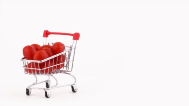 Yarım çerçeve. Süpermarket arabası kırmızı kiraz domates kazık su damlaları ile dolu. Turntable döner. Beyaz arka plan üzerinde izole. Yakın çekim. Makro.