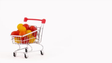 Yarım çerçeve. Süpermarket arabası kırmızı ve Sarı kiraz domates kazık su damlaları ile dolu. Turntable döner. Beyaz arka plan üzerinde izole. Yakın çekim. Makro.