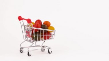 Süpermarket arabası hareket çok renkli üzüm domates yığın ile Paketli. Beyaz arka plan üzerinde izole. Yakın çekim. Makro.