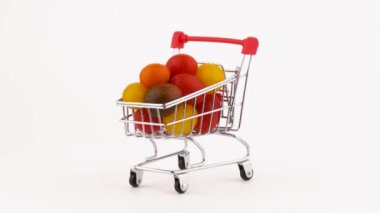 Alışveriş sepeti çok renkli üzüm domates kazık su damlaları ile dolu. Turntable döner. Beyaz arka plan üzerinde izole. Yakın çekim. Makro.