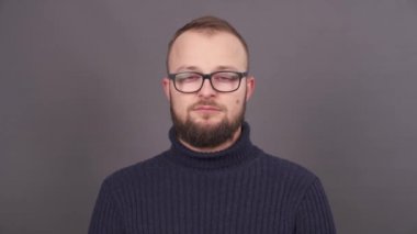 Neredeyse gözlerini saklayabileceğini gözlüklü Genç sakallı uykulu adam portresi açın. Gri bir arka plan üzerinde izole.