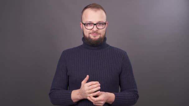 Nahaufnahme eines bärtigen jungen kaukasischen Mannes mit Brille, der sich die Finger massiert. isoliert auf grauem Hintergrund. — Stockvideo