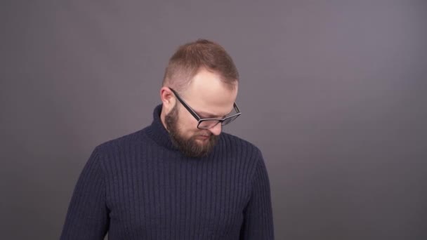 Retrato de cerca de un joven hombre caucásico barbudo con gafas cayendo confundido y avergonzado. Aislado sobre fondo gris . — Vídeo de stock