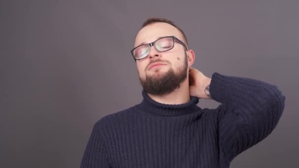 Portrait d'un jeune homme barbu fatigué massant son cou. Isolé sur fond gris . — Video