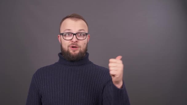 Gros plan portrait de jeune homme caucasien barbu dans des lunettes comptant de un à cinq doigts. Isolé sur fond gris . — Video