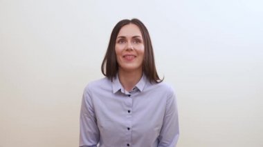 Bir esmer mutlu görünüyor, gülümsüyor, kafa sallıyor, kameraya doğru görünüyor, yine gülümsüyor