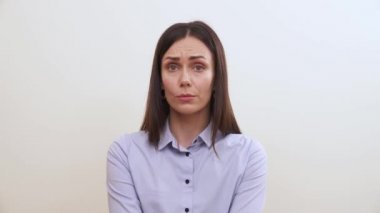 Bir esmer sağa doğru görünüyor, frowns, sol yanağında bir parmak ile dokunur, ayağa kalkar ve goes uzağa