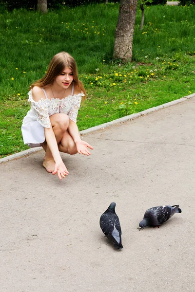 Güvercinler beyaz elbiseli yalınayak bir sarışın kız beslemeleri.
