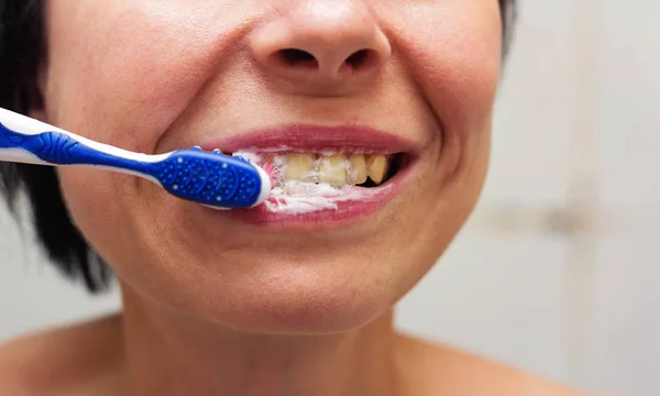 Bir kadın ile bir diş fırçası diş macunu ile diş temizleme.