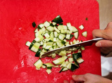 Bir kadın bir salatalık salatası için küçük parçalar halinde keser..