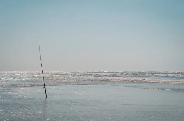 Fishing on the beach, fishing rod in the sand on the beach.