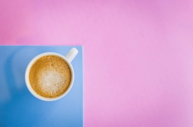 Beyaz fincan kahve açık pembe ve açık mavi renkli üzerinde.