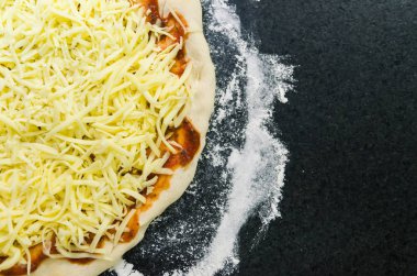 Pizza, pizza hamur domates sosu ve mozzarella peyniri ile yakın çekim hazırlanıyor.