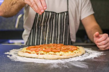 Adam siyah granit masada pepperonili pizza hazırlıyor.