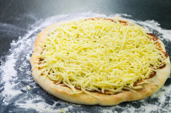Pizza, pizza hamur domates sosu ve mozzarella peyniri ile yakın çekim hazırlanıyor.
