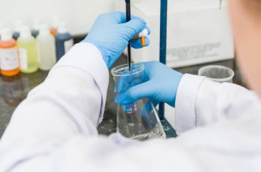 Kadın elleri kimyasal kalite kontro üzerinde titre testi yapıyor.