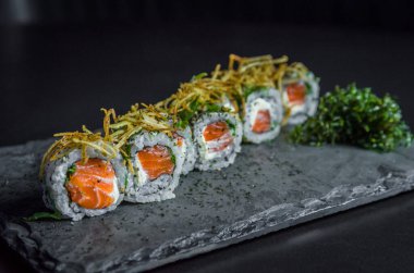 Suşi, geleneksel Japon mutfağı. Süslü tabakta nefis Uramaki, siyah arka plan.
