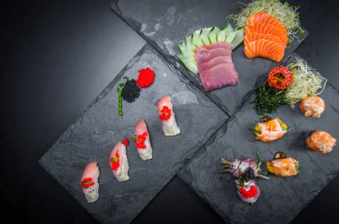 Suşi, geleneksel Japon mutfağı. Süslü tabakta bir sürü lezzetli suşi, siyah arka plan. Suşi, Urakami, Nigori, suşi jow, sashimi, tekamaki vs. ...