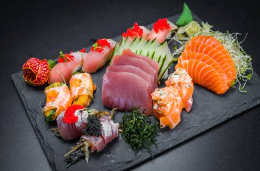 Suşi, geleneksel Japon mutfağı. Süslü tabakta bir sürü lezzetli suşi, siyah arka plan. Suşi, Urakami, Nigori, suşi jow, sashimi, tekamaki vs. ...