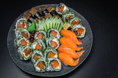 Suşi, geleneksel Japon mutfağı. Süslü tabakta bir sürü lezzetli suşi, siyah arka plan. Suşi, Urakami, Nigori, suşi jow, sashimi, tekamaki vs. ...