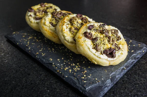 Delicious Lebanese (Arabic) food, Mediterranean ricotta sfiha, olives au gratin with cheese on black granite background.