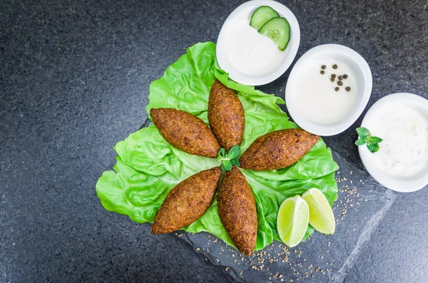 Delicious Lebanese (Arabic) food, kibbeh (kibe) on black slate stone and granite background.