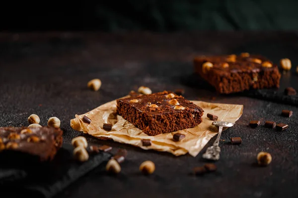 Brownie cake wit hazelnut and chocolate on dark grunge table — Stock Photo, Image