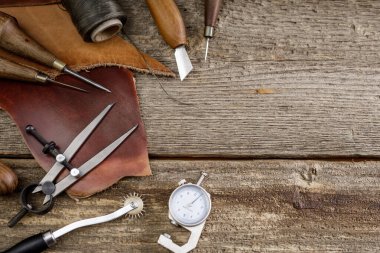 Kulübedeki eski ahşap masada deri el işi aletleri. Deri ustası çalışma alanı. Koyu ahşap dokusunu öğüt.
