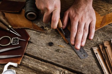 Kulübedeki eski ahşap masada deri el işi aletleri. Deri ustası çalışma alanı. Koyu ahşap dokusunu öğüt.