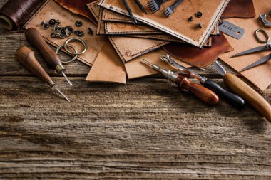 Kulübedeki eski ahşap masada deri el işi aletleri. Deri ustası çalışma alanı. Koyu ahşap dokusunu öğüt.