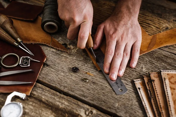 Primo piano di un calzolaio o di un artigiano. Utensili artigianali in pelle su vecchio tavolo in legno. Laboratorio artigianale in pelle. — Foto Stock