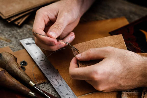 Близько до взуття або рук майстра. Шкіряні інструменти для ремесел на старому дерев'яному столі. Шкіряна майстерня ремесел . — стокове фото
