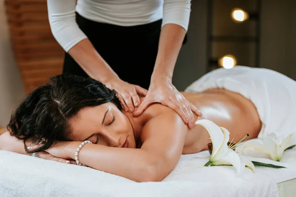 Massagista fazendo massagem no corpo bela jovem no salão de spa. Profissional masseur e clien conceito. — Fotografia de Stock