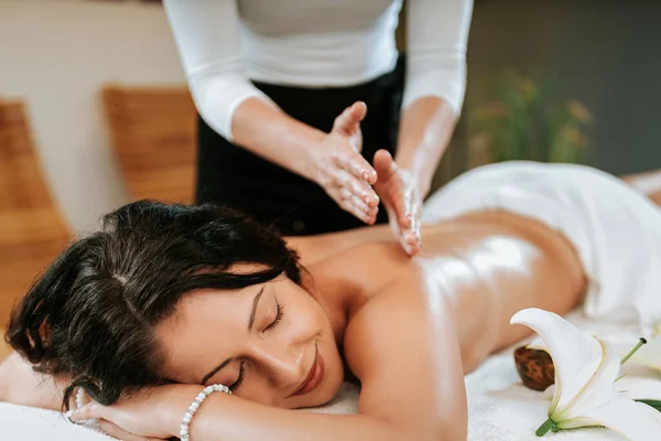 Mulher bonita no salão de massagem com cabelo encaracolado marrom e pele saudável. Conceito de massagista e paciente. — Fotografia de Stock