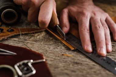 Ayakkabıcı ya da zanaatkar işçilere yakın çekim. Eski ahşap masadaki deri el aletleri. Deri sanatları atölyesi.