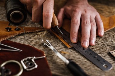 Ayakkabıcı ya da zanaatkar işçilere yakın çekim. Eski ahşap masadaki deri el aletleri. Deri sanatları atölyesi.